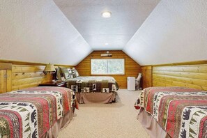 Un dormitorio con dos camas, una ventana y un ventilador de techo.