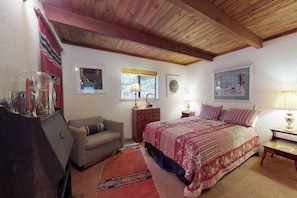 A bedroom with a bed, a sofa, a dresser, and a lamp. - Forest Chalet - Pine Mountain Lake (Groveland)