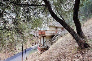 A two-story house with a balcony, surrounded by trees and a sloped driveway. - Forest Chalet - Pine Mountain Lake (Groveland)