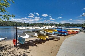 Une rangée de canoës et de kayaks était alignée sur une plage de sable, au bord d’un lac paisible.