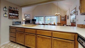 Una cocina con armarios de madera, una isla grande y un comedor con sillas.