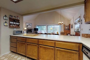 A kitchen with wooden cabinets, a large island, and a dining area with chairs.