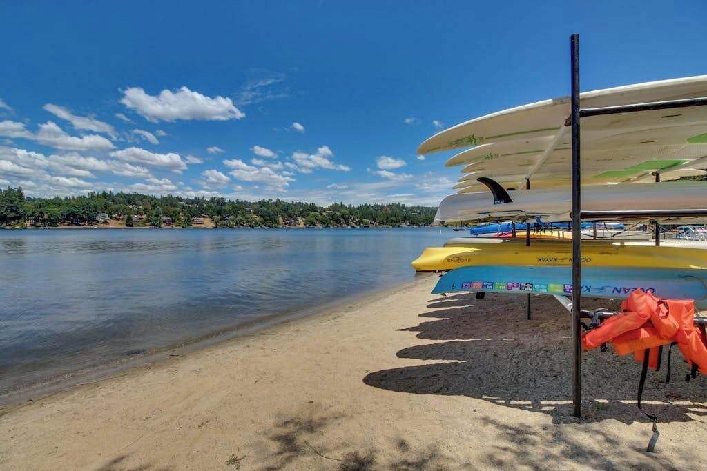 Un entorno junto al lago con una hilera de canoas y kayaks amarrados en una orilla arenosa.