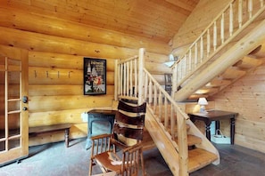 A wooden interior with a spiral staircase, a bench, a chair, and a poster on the wall. - Logger's Landing - Huntington Lake (Lakeshore)