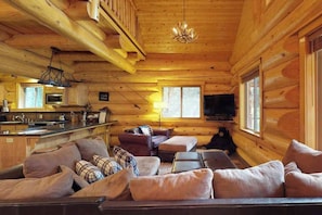 A log cabin interior with a living area, kitchen, and a television. - Logger's Landing - Huntington Lake (Lakeshore)