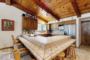 A kitchen with a large island, wooden cabinets, and a stone backsplash.