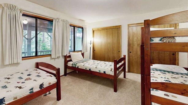 A room with three wooden bunk beds, a wooden wardrobe, and a window with curtains. - On The 9th - Blue Lake Springs (Arnold)
