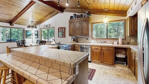 A kitchen with a large island, wooden cabinets, and a view of the outdoors. - On The 9th - Blue Lake Springs (Arnold)