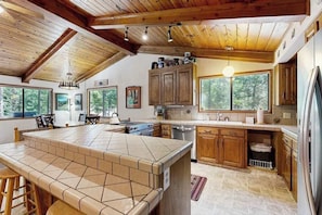 A kitchen with a large island, wooden cabinets, and a view of the outdoors.
