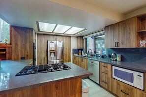 A modern kitchen with a central island, built-in appliances, and a skylight. - Tranquil Pines Retreat - Ridgetop (Shaver Lake)