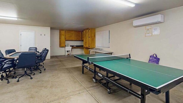 A room with a ping pong table, chairs, a small kitchenette, and a whiteboard. - Tranquil Pines Retreat - Ridgetop (Shaver Lake)