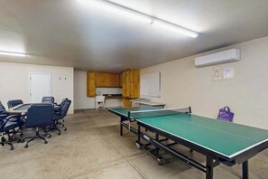 A room with a ping pong table, chairs, a small kitchenette, and a whiteboard. - Tranquil Pines Retreat - Ridgetop (Shaver Lake)