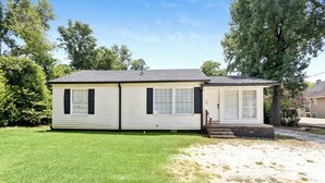 A single-story mobile home with a front porch, a small attached garage, and a well-maintained lawn. - Main House + Modern Tiny Home - 4 BR / 3 BA (Nacogdoches)