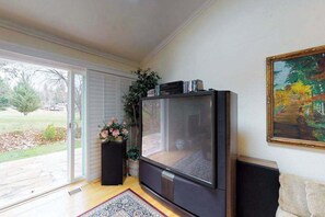 Un saló amb televisió de pantalla plana, un sofà, una taula de centre, una planta en test i un quadre a la paret.