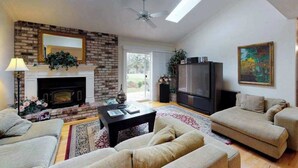 Una sala de estar con chimenea, sofá, televisor y ventilador de techo.