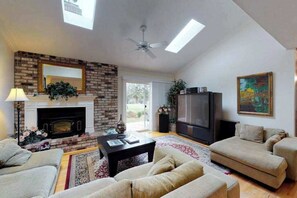 Ein Wohnzimmer mit Kamin, Sofa, Fernseher und Deckenventilator.