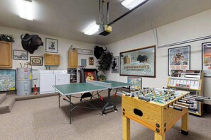 Habitació amb taula de ping-pong, taula de futbolí i zona de cuina americana.