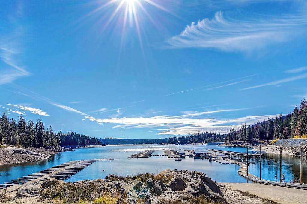 Vista despejada de un río con un muelle y un área boscosa al fondo.