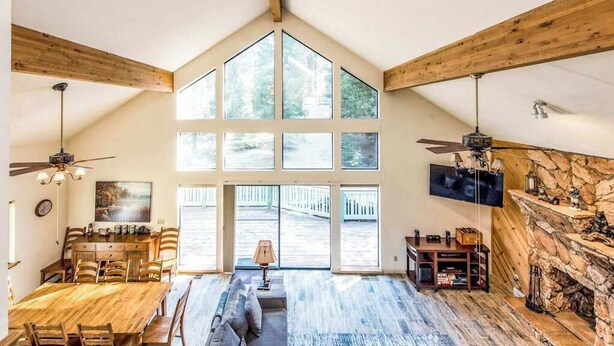 Un loft espacioso con techo alto, ventanas amplias, zona de comedor, sala de estar con chimenea y televisor montado en la pared.