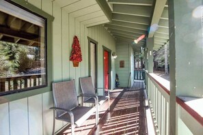 Eine überdachte Veranda mit Stühlen, einer roten Tür und einem hängenden Ornament.