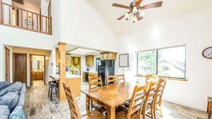 Amplia sala de estar con una mesa y sillas de comedor, una escalera y una cocina al fondo.