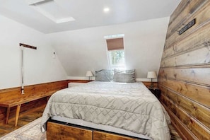 A bedroom with a bed, bedside tables, a bench, and a window. - Sparrow Cabin - East Village (Shaver Lake)