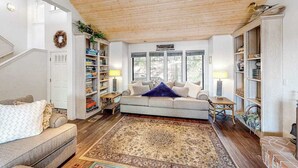 Un salon avec un canapé, une table basse, un tapis et des étagères.