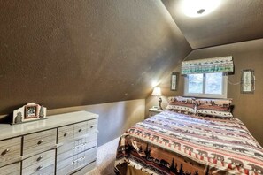 A bedroom with a bed, dresser, window, and a wall-mounted lamp. - The Limit - West Village (Shaver Lake)