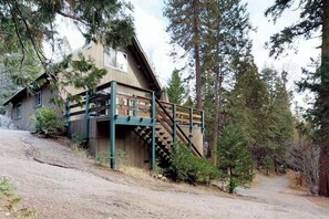 A cabin with a wooden exterior, a balcony, and a staircase leading to an upper level. - The Limit - West Village (Shaver Lake)