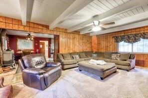 A cozy living room with a fireplace, leather sofa, and a ceiling fan. - The Limit - West Village (Shaver Lake)