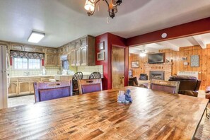 A dining area with a wooden table and chairs, a kitchen with wooden cabinets, and a fireplace. - The Limit - West Village (Shaver Lake)