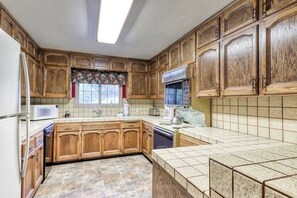 A kitchen with wooden cabinets, a microwave, a toaster, and a dishwasher. - The Limit - West Village (Shaver Lake)
