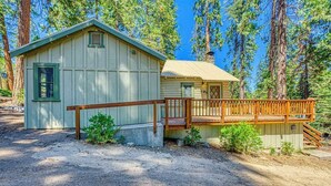 A cabin with a wooden deck and a dirt driveway. - Alpine Cottage - West Village (Shaver Lake)