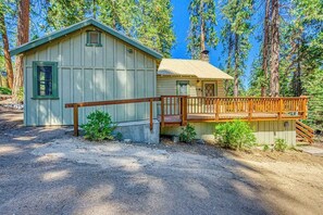 A cabin with a wooden deck and a dirt driveway. - Alpine Cottage - West Village (Shaver Lake)