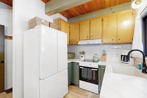 Una cuina amb armaris de fusta, un refrigerador blanc, una cuina i un rentavaixelles.