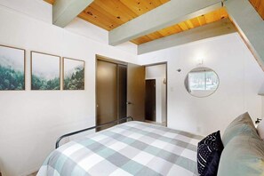 Un dormitorio con cama, armario, espejo y cuadros en la pared.