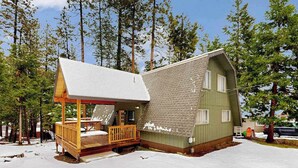 Uma cabana com varanda e deck, cercada por árvores.
