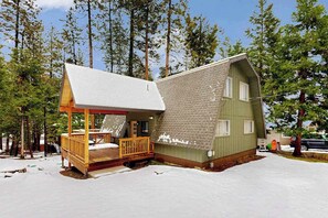 Eine Hütte mit Veranda und Terrasse, umgeben von Bäumen.