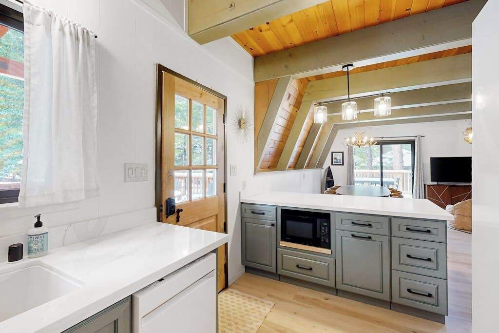 A modern kitchen with a large island, built-in appliances, and a wooden ceiling.
