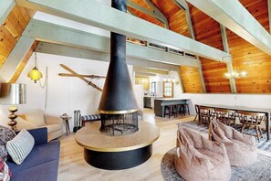 Ein großzügiger Loft mit hoher Decke, einem zentralen Kamin, einem Essbereich und einer gemütlichen Sitzecke mit Sitzsäcken.