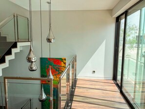 A modern interior with a staircase, glass railings, and a large window offering a view of the outdoors. - Villa with jacuzzi & heatable pool in Olhão (Olhão)