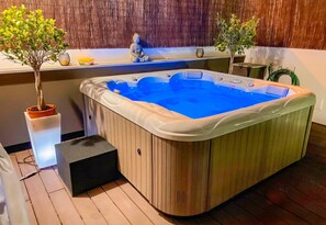 Ein Whirlpool mit Holzverkleidung, eine kleine Stufe zum Zugang und ein Bambus-Hintergrund.