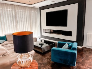 Ein modernes Wohnzimmer mit einer Couch, einem Couchtisch, einer Lampe und einem an der Wand montierten Fernseher.