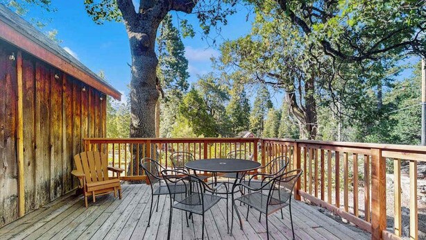 Eine Holzterrasse mit Tisch und Stühlen, umgeben von Bäumen.