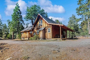 A wooden cabin with a porch, surrounded by trees. - Forest Edge Hideaway - Musick Meadows (Shaver Lake)