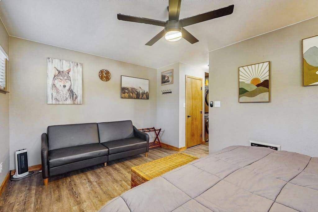 Une pièce comprenant un lit, un canapé, un ventilateur de plafond et des œuvres d’art accrochées aux murs.
