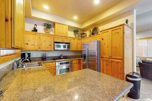 A kitchen with granite countertops, wooden cabinets, stainless steel appliances, and a trash can. - Baby Bear Bliss - Sierra Pines (Shaver Lake)