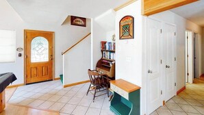 Een kamer met een houten deur, een piano, een stoel en een boekenkast.