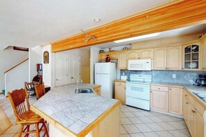 Una cocina con armarios de madera, encimera de mármol y horno empotrado.