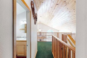 A wooden staircase leading to a balcony with a view of a circular window and a ceiling with exposed beams. - Papa's Mountain Retreat - Shaver Lake (Shaver Lake)